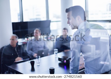 Business man making a presentation at office. Business executive delivering a presentation to his colleagues during meeting or in-house business training, explaining business plans to his employees. Royalty-Free Stock Photo #274821560
