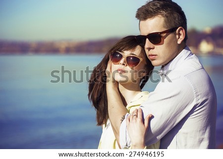 Cheerful couple embracing and posing on the beach on a sunny day. Picture (photo) of a happy couple having fun on the beach. Hipster style. Outdoor shot