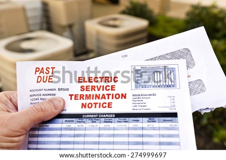 Hand Holding Electric Service Termination Notice In Front Of Air Conditioning Units Royalty-Free Stock Photo #274999697