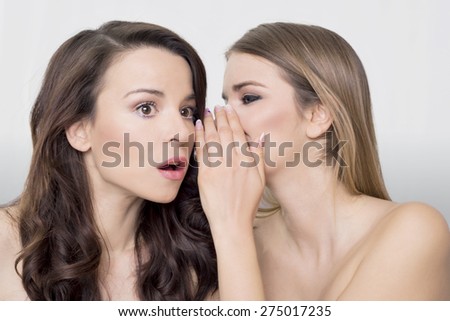 Woman whispering in ear, acting surprised