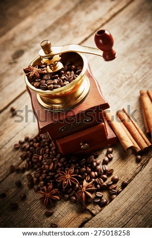 Coffee beans, coffee grinder, cinnamon and anise on wooden background