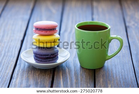 Cup of coffee and macarons on old wooden table.