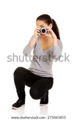 Teen woman taking a photo with a camera.