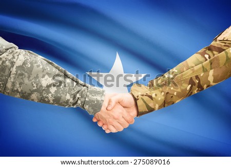 Soldiers shaking hands with flag on background - Somalia