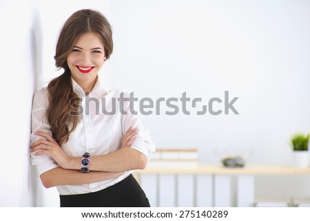 Attractive businesswoman standing near wall in office. Royalty-Free Stock Photo #275140289