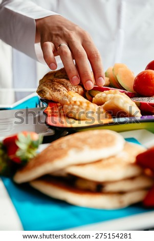 Close Up Of Arabian Man's Hand Taking Freshly Prepared Pastry From Plate With Delicious Breakfast