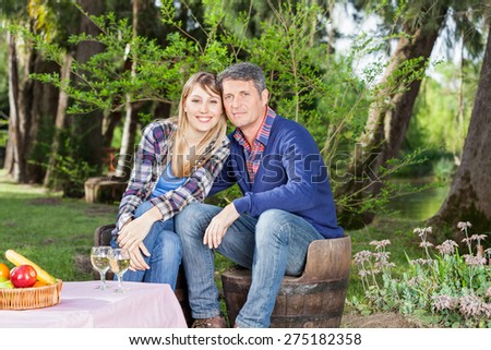 Portrait of happy couple sitting on chairs at campsite