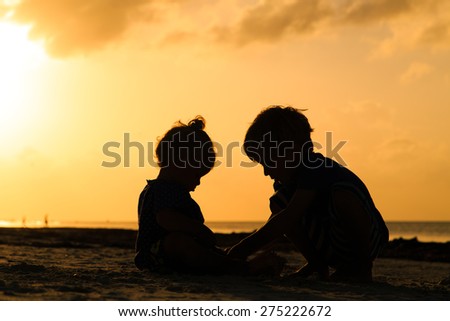 little boy and toddler girl playing at sunset beach