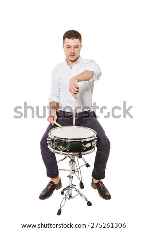 Handsome guy in a white shirt teaches properly play the drums on a white background