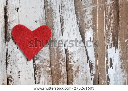little red heart in felt on whitened wooden background