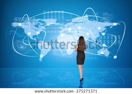 Businesswoman in black dress with crossed arms in front of holographic screen, back view