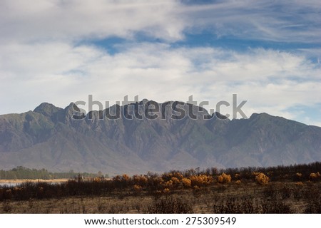 Lake in South Africa with mountains in the background and burned bushes in the foreground, 