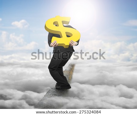 Businessman carrying big 3D gold dollar sign balancing on concrete ridge with sky cloudscape sunlight background