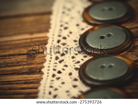 Vintage lace ribbons and buttons set on an old wooden table, close up. Shallow depth of field.  instagram image retro style.