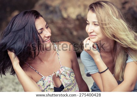 Pretty beautiful girl friends  having fun. Both looking at camera and smiling (laughing). Concept of female friendship.