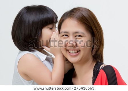 Portrait of Asian mother whispering to her daughter on isolated