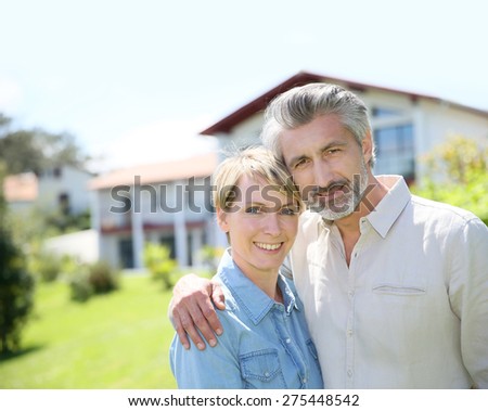 Couple standing in front of newly owned house Royalty-Free Stock Photo #275448542