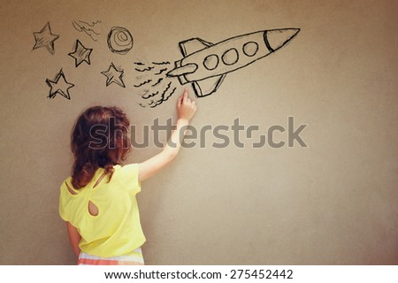 back view of cute kid (girl) imagine space rocket with set of infographics over textured wall background
