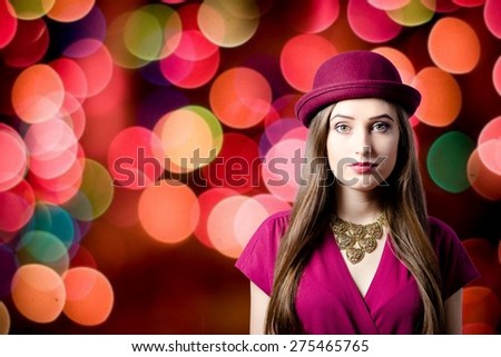 Portrait of elegant beautiful young lady in red hat looking in camera over bright party bokeh background