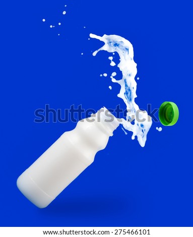 Pouring milk in a  bottle on blue background