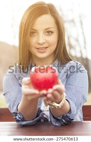 Young woman eating an apple at park