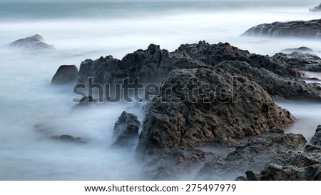 Peaceful seascape with coastline, cliff, rock and stones in sea water. Long exposure shot