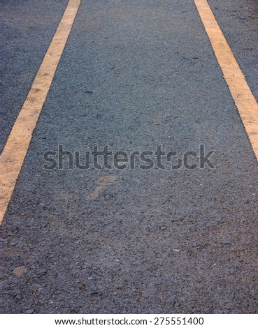 close up of a dark grey asphalt road divided by yellow paint