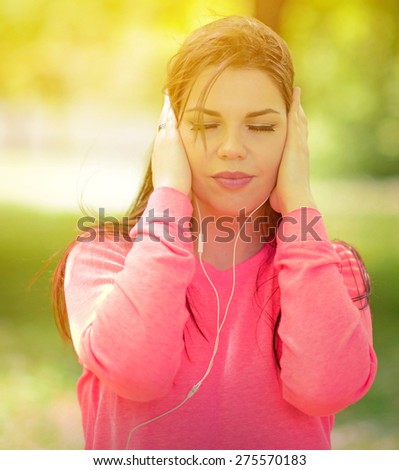 Female student girl outside in park listening to music on headphones