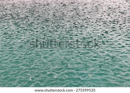 weather, rain, met cast, season and natural phenomenon concept - water surface with raindrops