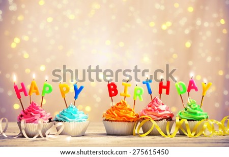 Delicious birthday cupcakes on table on light background
