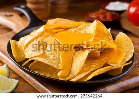 A plate of delicious plain nacho tortilla corn chips with cheese sauce. Royalty-Free Stock Photo #275642264