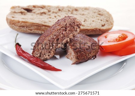 ripe beef meat hamburger on white plate with rye bun on white plate with cutlery on tablecloth