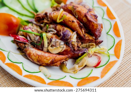 Grilled squid with vegetables on a white plate. Restaurant