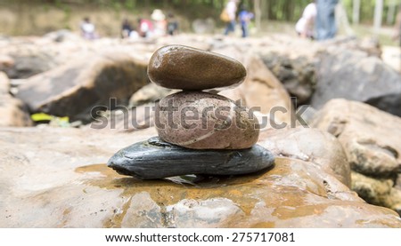 Stack of pebble stones by a stream , river background