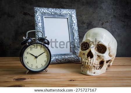 Still life with vintage photo frames, vintage clock and skull on wooden table over grunge background