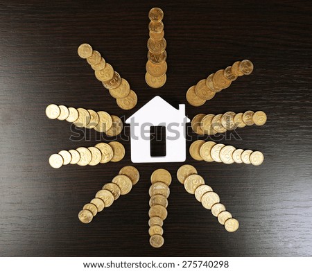 Model of house with coins on wooden table, closeup