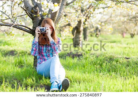 Young teen girl with retro camera in the blossom apple garden