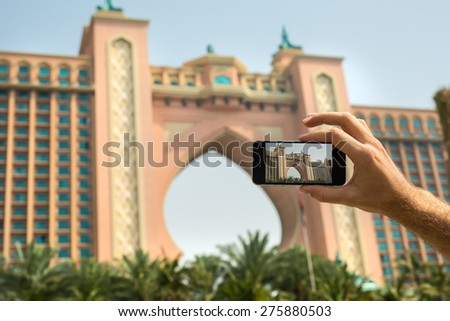 Hand tourist takes a picture of the hotel Atlantis on a mobile phone. Dubai. UAE.