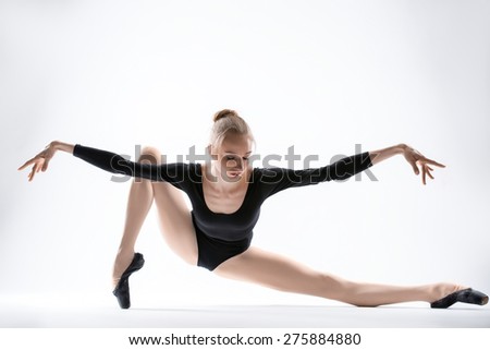 Graceful ballerina in black leotard doing stretching. Isolate on a white background in the studio.