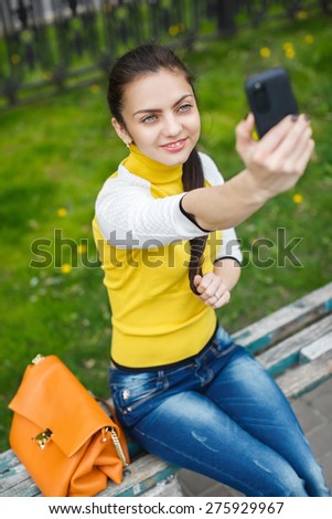 smiling  girl taking picture with smartphone camera outdoors. selfie