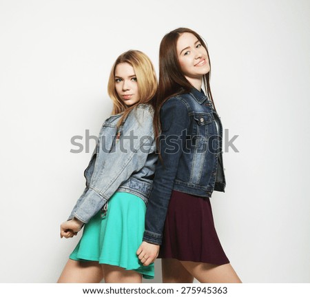 Two young girl friends standing together and having fun. Looking at camera.
