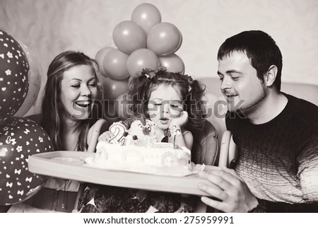 toddler girl and her parents sitting with birthday cake