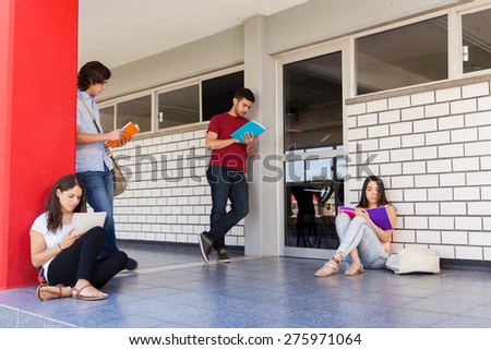 Bunch of college students waiting in the hallway outside a classroom and studying before a test