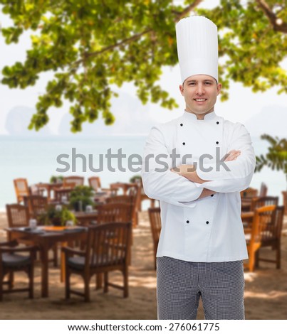 cooking, profession and people concept - happy male chef cook with crossed hands over restaurant lounge on beach