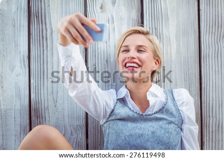 Pretty blonde woman taking selfie on wooden background