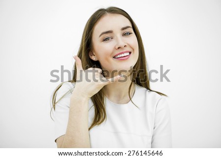 Young happy smiling brunette woman with call me gesture, against white background