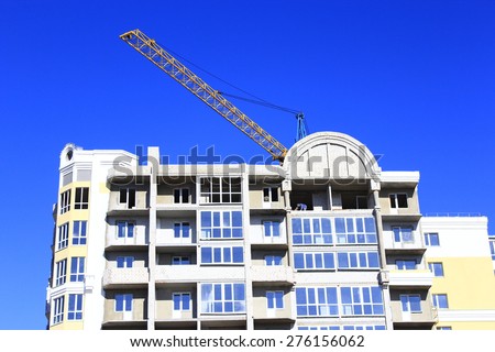 construction of multistorey modern house with hoisting crane on the blue sky background
