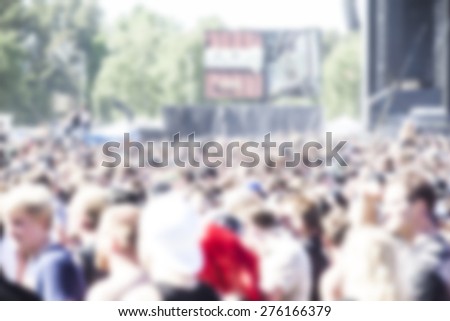 Large crowd of people watching rock concert, festival spring summer time , blurred background
