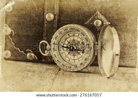 antique compass on wooden table. black and white style old photo
