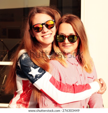 Close up fashion portrait of two sisters hugs and having fun together, wearing bright stylish mirrored sunglasses, best fiend enjoy amazing time together.